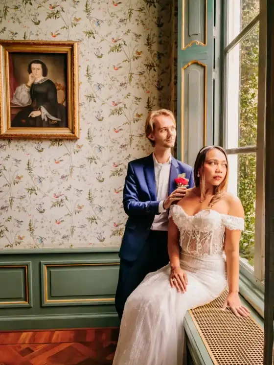 Bruidspaar bij een raam met een rode roos, sfeervolle bruidsfotografie door Indra Hunze