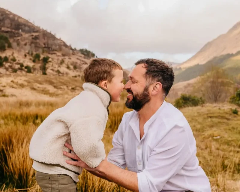 Vader en zoon neus aan neus in een open landschap, gezinsfotografie door Indra Hunze