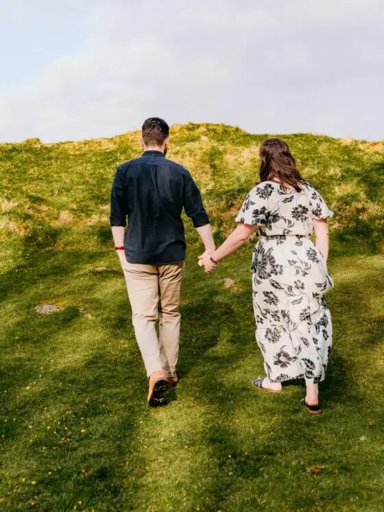Koppel hand in hand wandelend door het landschap, tijdloze fotografie door Indra Hunze